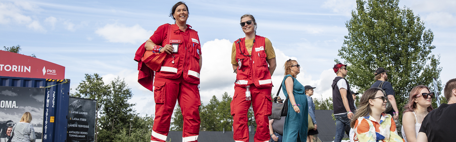 Kaksi Suomen Punaisen Ristin vapaaehtoista kävelee festivaalialueella ensiapupakkauksen kanssa.