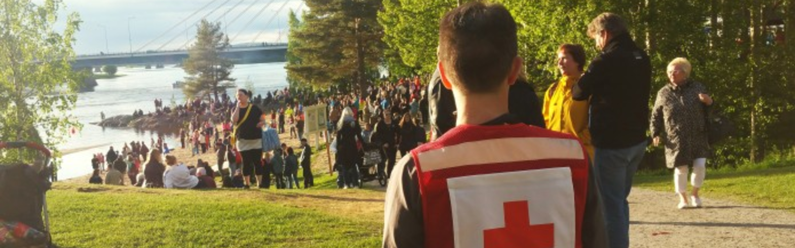 Suomen Punaisen Ristin vapaaehtoinen katsoo ihmisjoukkoa Rovaniemellä.