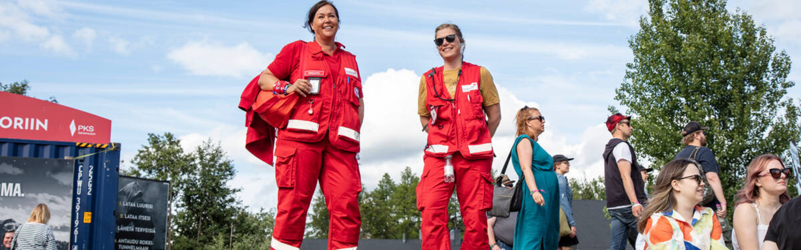 Kaksi Suomen Punaisen Ristin vapaaehtoista kävelee festivaalialueella ensiapupakkausten kanssa.