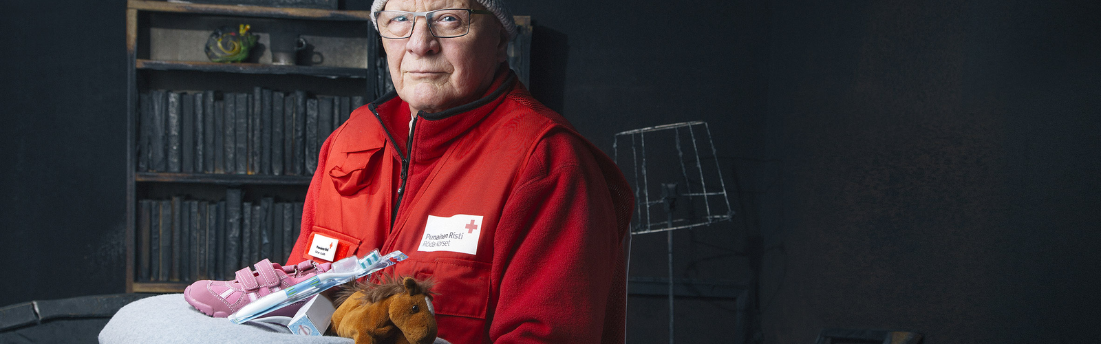 Punaisen Ristin vaatteisiin pukeutunut mies pitää käsissään avustustarvikkeita.