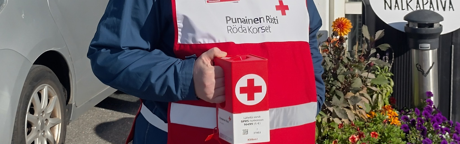 Kerääjä punaisessa liivissä lippaan kanssa