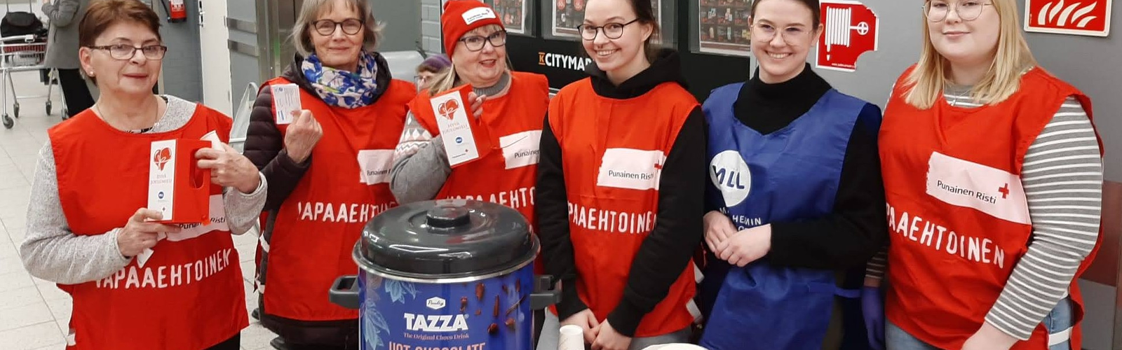 Hymyilevät vapaaehtoiset keräyspisteellä sisätiloissa.