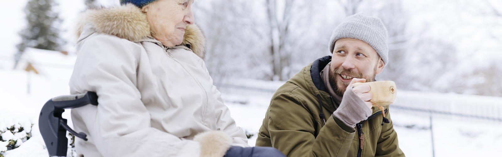 Kaksi henkilöä istuvat vierekkäin talvisessa maisemassa