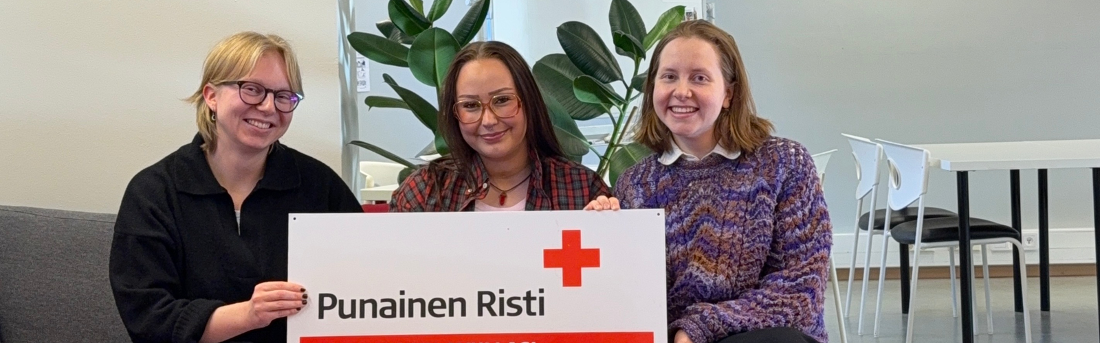 Harjoittelijat istumassa sohvalla Punaisen Ristin kyltin kanssa