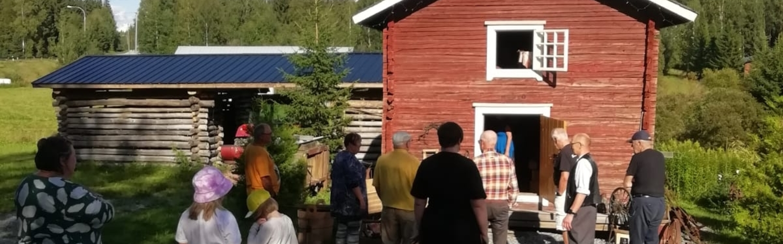ihmisiä keväällä ulkona punaisen ladon edessä