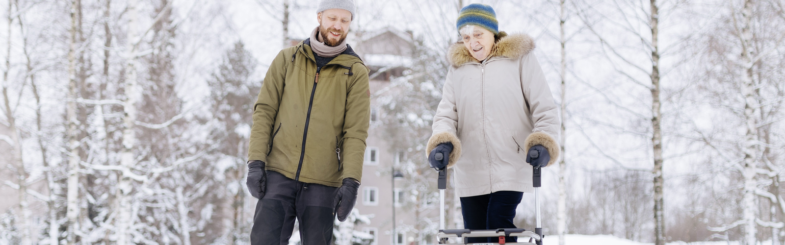 Nuori mies ja vanha nainen kävelyllä talvisessa maisemassa